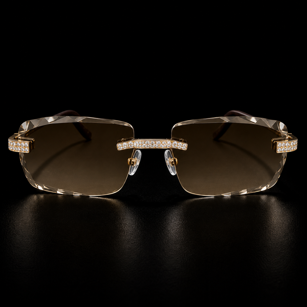 Rimless square sunglasses with gold-tone metal frames, crystal-studded brow bars, and brown gradient lenses, displayed on a reflective black surface.