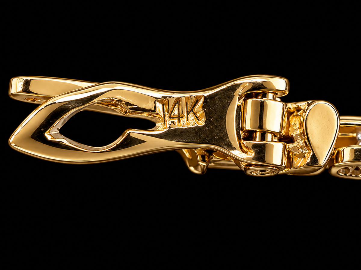 Close-up of a polished yellow gold bracelet clasp with a heart-shaped accent and a partially visible diamond-set section, shown against a solid black background.