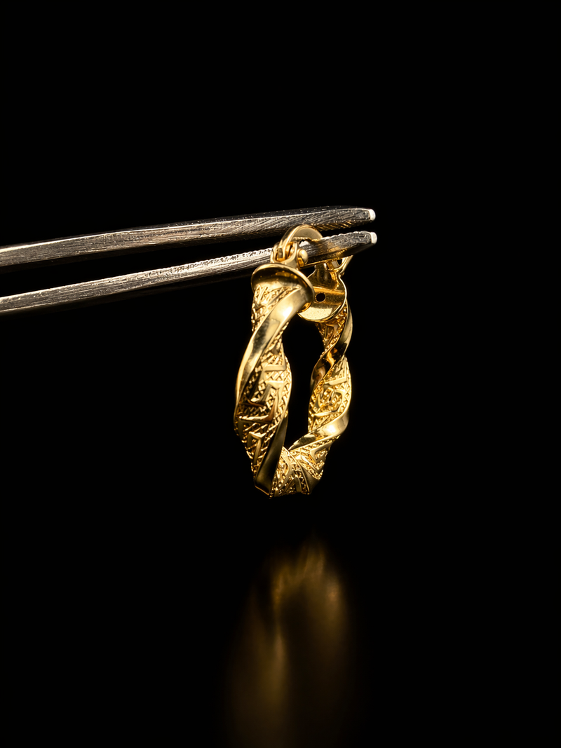 Gold ring held by tweezers against a black background