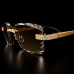 Luxury rimless sunglasses with gold-tone metal frames, crystal-cut transparent lenses, and rows of sparkling clear rhinestones on the brow bar and temple arms, set against a solid black background.