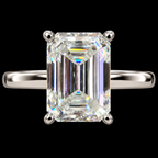 An emerald-cut diamond ring with a silver-colored band, set against a solid black background.